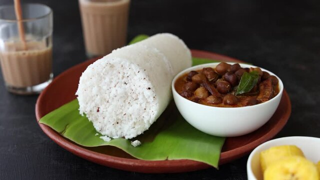 Pouring Indian milk tea with Rice Puttu white Pittu Kadala Chickpea curry popular South Indian breakfast steamed rice cake 4K video footage Kerala Tamil Nadu India Sri Lanka. rice flour grated coconut