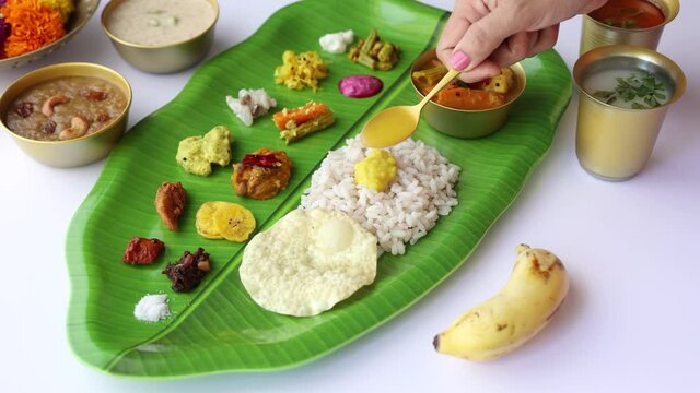 Woman hand serving  parippu dal curry ghee traditional Onam sadhya 4K  rice Sambar, Rasam,  Avial,  Pappadom Payasam on banana leaf Onam Vishu Indian festival vegetarian food Kerala South India.