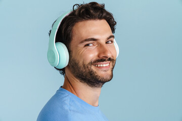 Young brunette man with bristle listening music with headphones