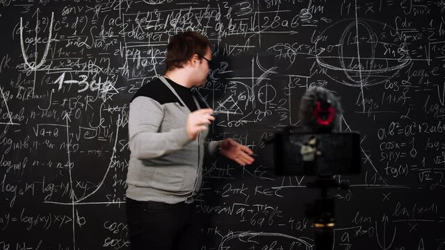 Teacher explains new material online during distance education of quarantine. Professor draws triangle and proves theorem standing at blackboard in front of smartphone camera. Concept of e-learning.