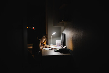 teenage girls, high school girl doing homework at the table in a dark room