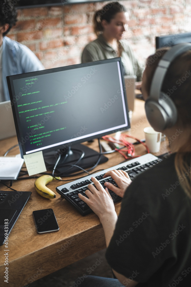 Wall mural high angle view of female hacker coding over computer in office