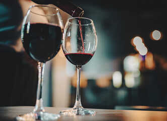 waiter pouring red wine into a glass in cafe or bar