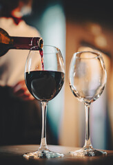 waiter pouring red wine into a glass in cafe or bar