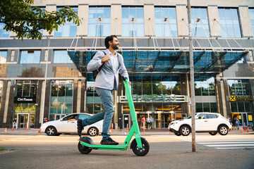 Young white man smiling while riding powered scooter at city street