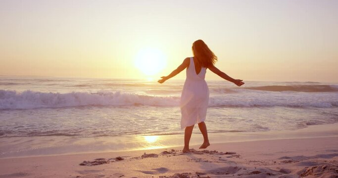 Free happy woman spinning arms outstretched enjoying nature dancing on beach at sunset slow motion RED DRAGON