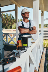 Construction worker folding hands on house porch