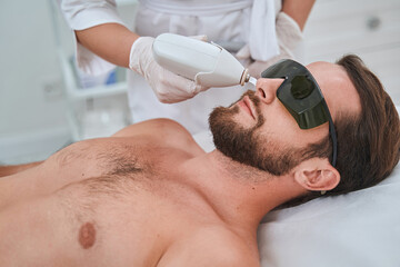 Young spa client in safety goggles during a cosmetic procedure