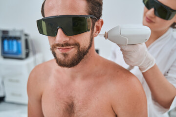 Man wearing protective eyeglasses during the laser ear hair removal treatment