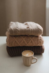 cozy comfortable hygge home atmosphere and still life with a cup, candle and sweaters