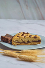 Slice of homemade chocolate cake with chocolate chips on a marble table.