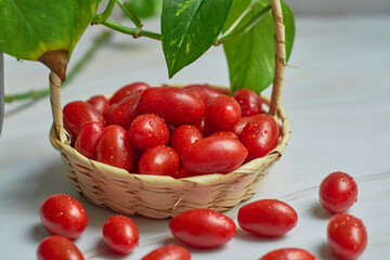 Stack of wet cherry tomatoes in a wooden basket, freshly harvested.