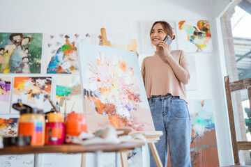 busy painter standing next to her painting while calling by her phone