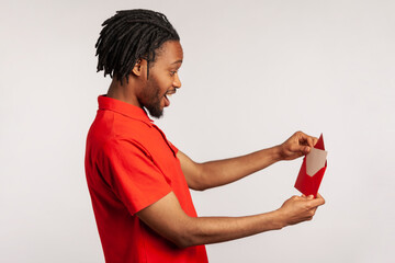 Side view of positive man with dreadlocks wearing red casual style T-shirt, opening letter in red...