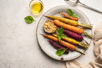 Roasted young whole colorful carrot with herbs served on plate over white background. Top view