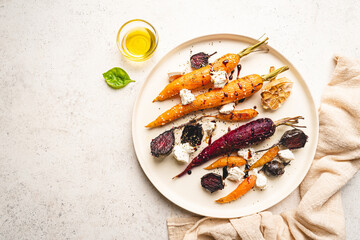 Roasted young whole colorful carrot with herbs and cheese served on plate over white background. Top view