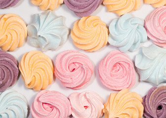 Meringues Closeup of mini color sweets on white sweets background. top view