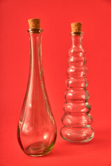 Empty glass bottle with original shapes on a solid neutral colored background.
