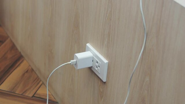 The white mobile battery charger is plugged into the wall socket.