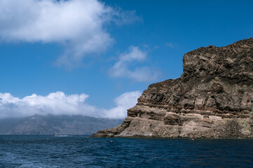 Scenic landscape of Aegean sea at sunny summer day. Cliff of Santorini island. Silhouettes of islands in mist.