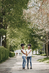 Twin sisters holding hands and walking in a park