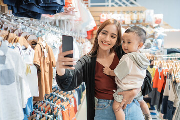 asian mother take selfie with her son while shopping in the mall