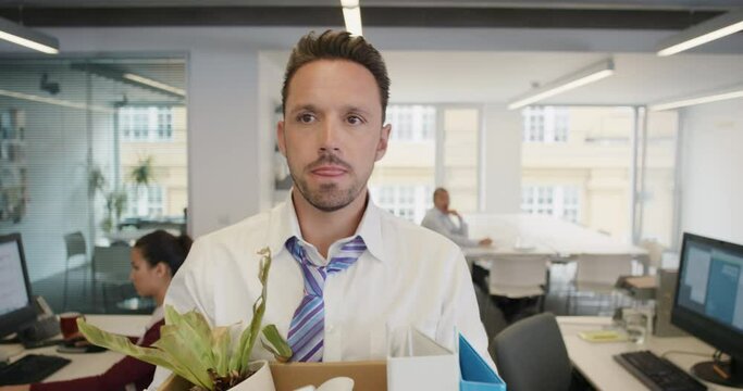 Businessman getting fired carrying box of personal belongings being made redundant in recession sad worried failure