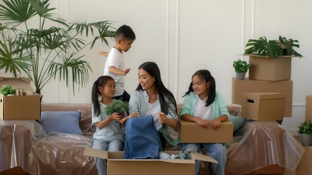 Asian Family Moving House Packing Boxes And Having Fun Indoor