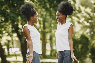 Twin sisters standing in a park and looking on each other