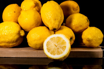 photo of lemons in still-life style, on wooden surface resting on reflective black table