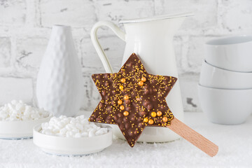 Star shaped chocolate lolly with gold sugar pearls on white background