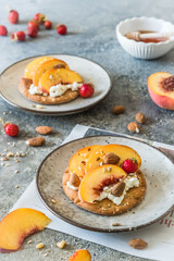 Round crispbread slices with grainy cream cheese and fresh peaches, healthy breakfast, vertical