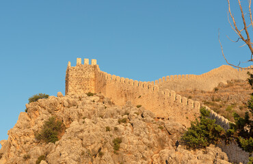 The fortress wall against the background of a bright blue sky on a sunny day in Alanya.