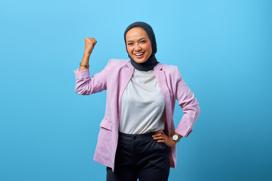 Portrait of attractive Asian woman demonstrates strong hand over blue background