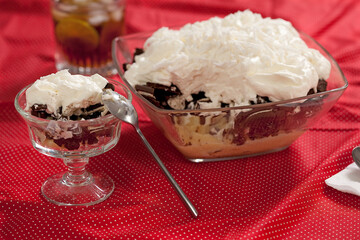 Doce com biscoito de chocolate e creme de baunilha e merengue de cobertura sobre mesa decorada.