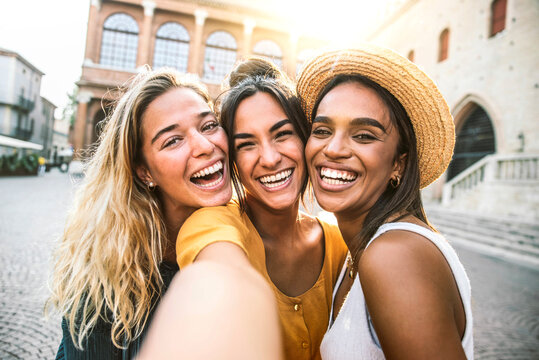 Fototapeta Three young women taking selfie portrait on city street - Multicultural female friends having fun on vacation hanging outdoor - Friendship and happy lifestyle concept