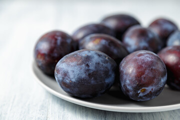 Fresh plums. Fruits. On a white wooden background. Copy space.