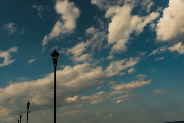 Street lamps in foreground of sky background, lined up at an angle. 