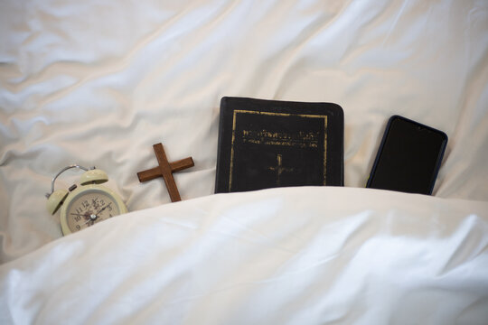 Alarm clock and the Bible on bed prepare for Bible study.