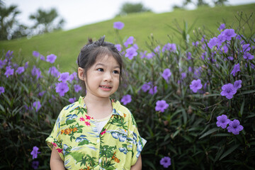 Happy little girl with purple flowers in summer.