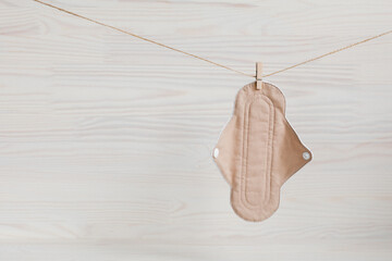 Eco-friendly reusable organic bio-cotton pad hanging on a rope on a wooden background with Gypsophila. Zero waste reusable washable cloth pad.