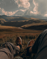 person sitting on the grass admiring the high snow-capped peak