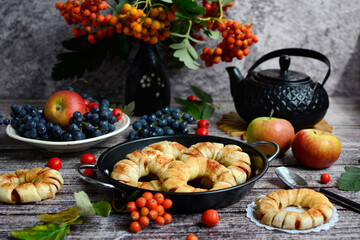 Dessert apple rings with cinnamon. Homemade baking. Autumn still life with rowan branches, juicy apples, pastries on a rustic background
