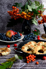 Beautiful vertical composition. Apples, grapes, rowan branches and homemade cakes with apples on a dark wooden background