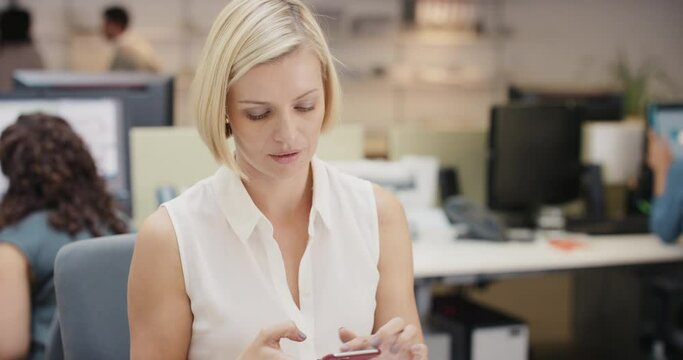 Powerful Businesswoman executive working at computer using smart phone connected to global data in busy corporate office