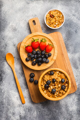 A bowl of cereal with blueberries and a plate of blueberries and strawberries