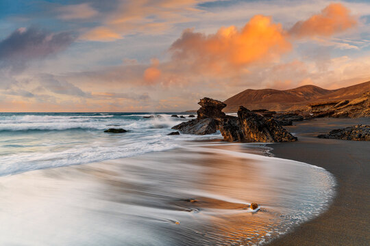 Waves crashing on sandy beach Playa de la Solapa at sunset, Fuerteventura, Canary Islands
