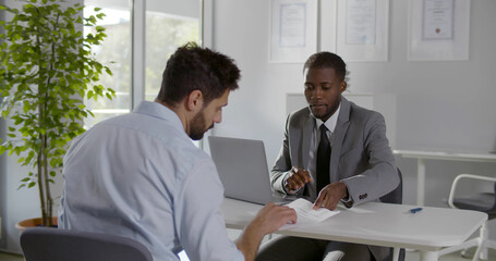 Diverse business partners sign contract in modern office