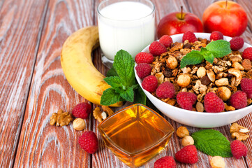 A bowl of crispy granola with fresh raspberries for breakfast on a wooden background. Healthy breakfast in the morning. ?lose-up. Copy space.