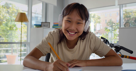 Korean teen girl in headphones distance learning during virtual online class